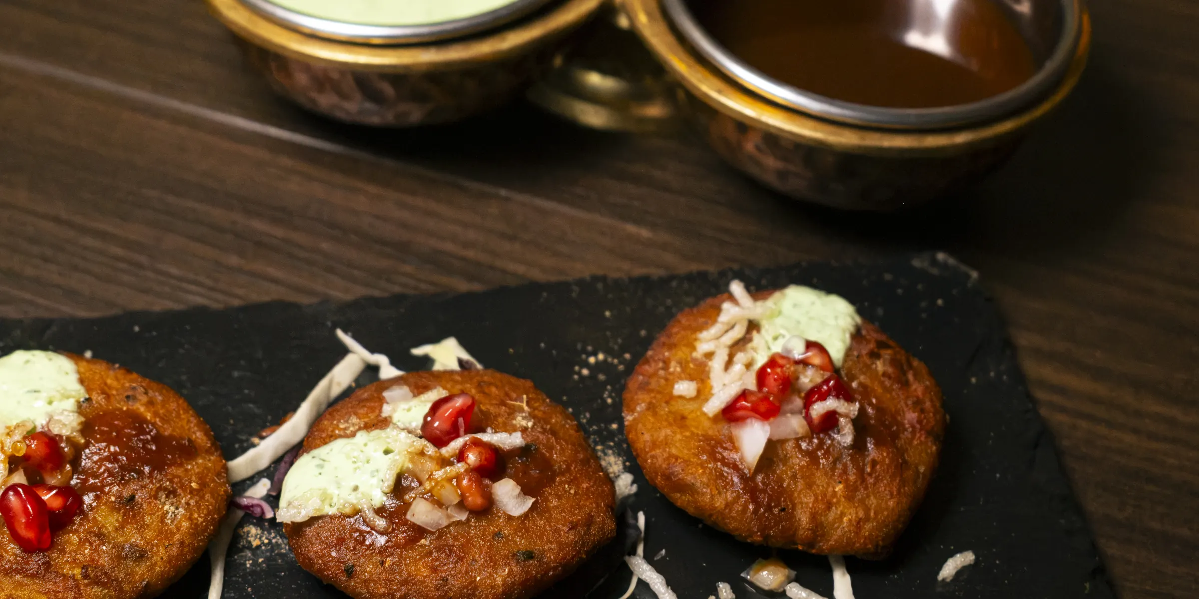 Aloo Tikki sulla lavagna con il portasalse in ottone