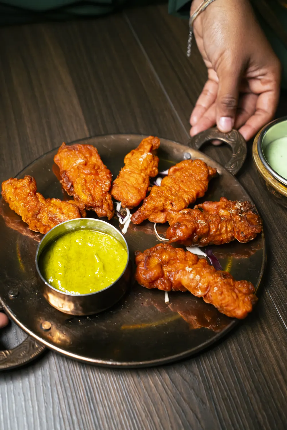 Pakoda di pollo con chutney alla menta sul vassoio in rame