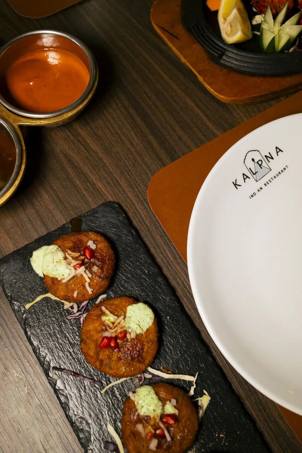 Aloo Tikki sulla lavagna accanto al piatto col logo Kalpna