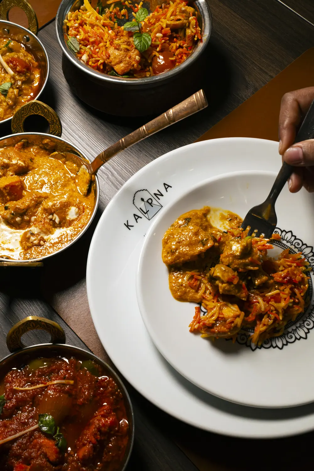 Curry nelle ciotole in rame e il piatto col logo Kalpna