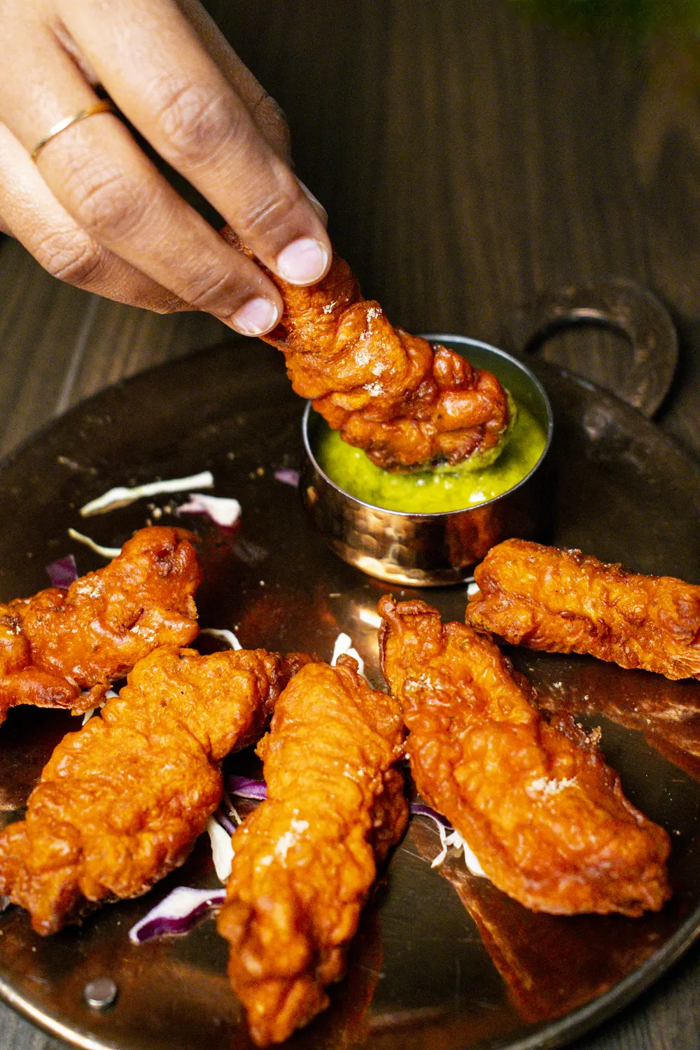 Un pakoda di pollo intinto nel chutney alla menta