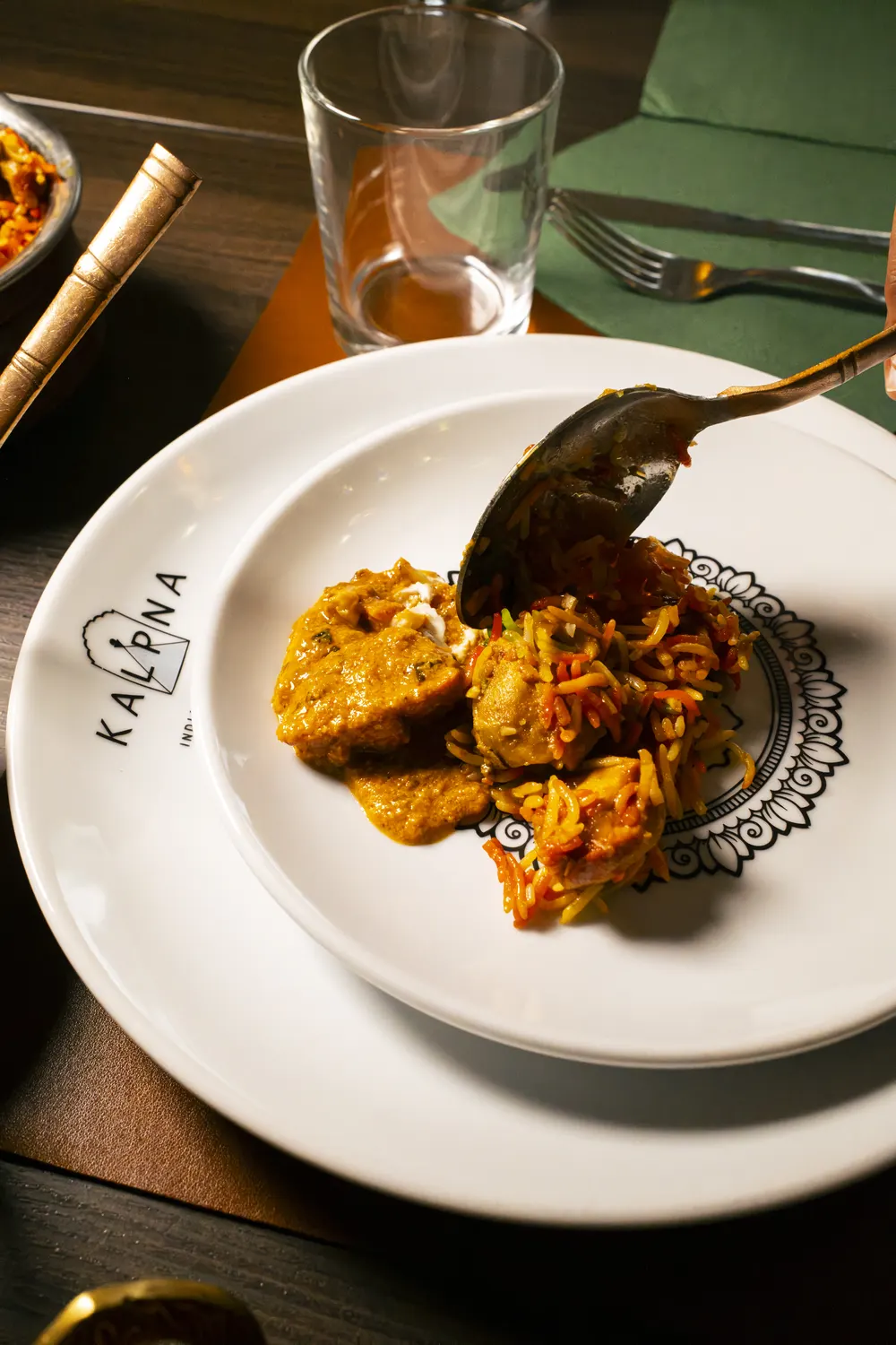 Biryani servito col cucchiaio nel piatto col logo Kalpna