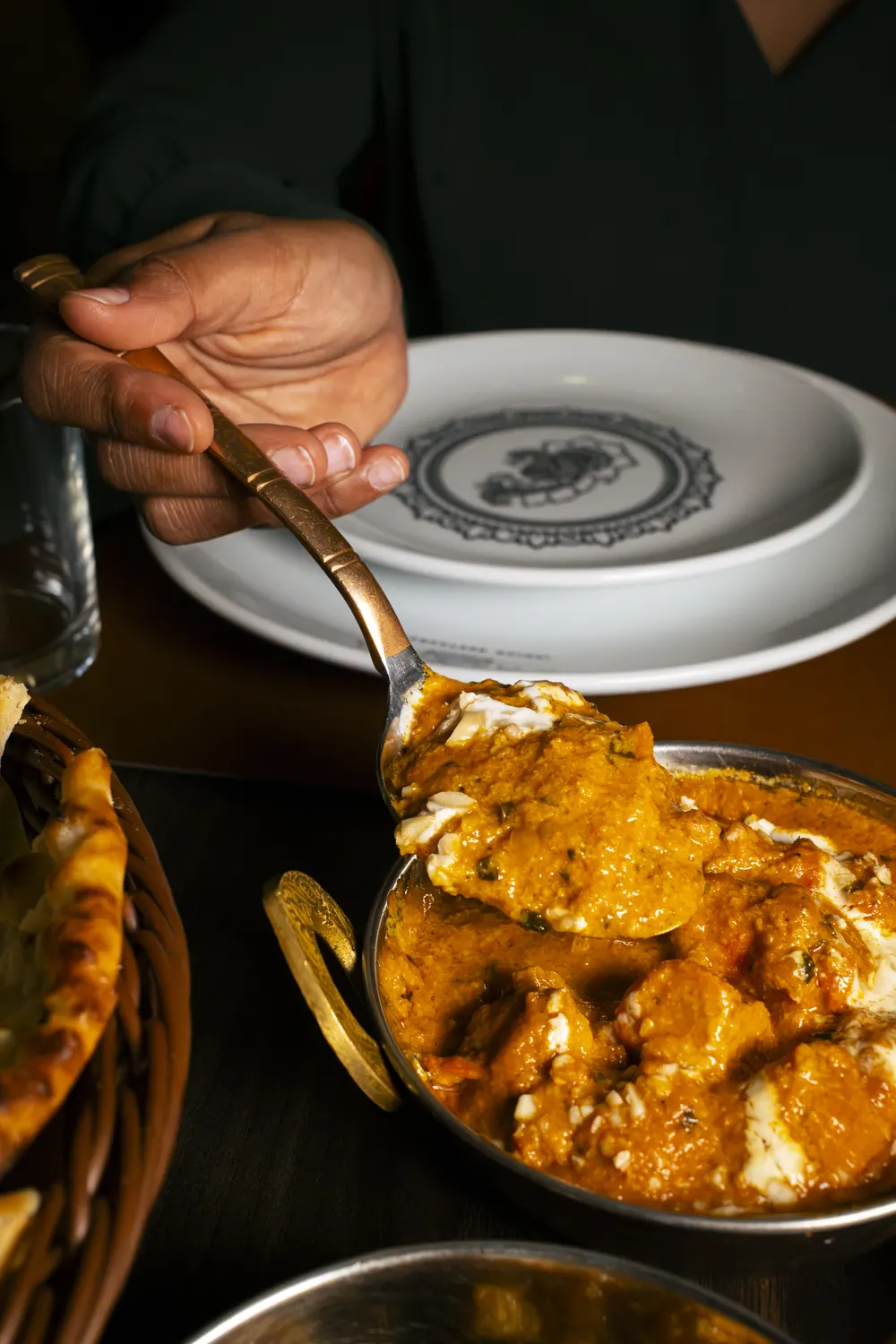 Curry servito al tavolo, accanto a un cesto di naan