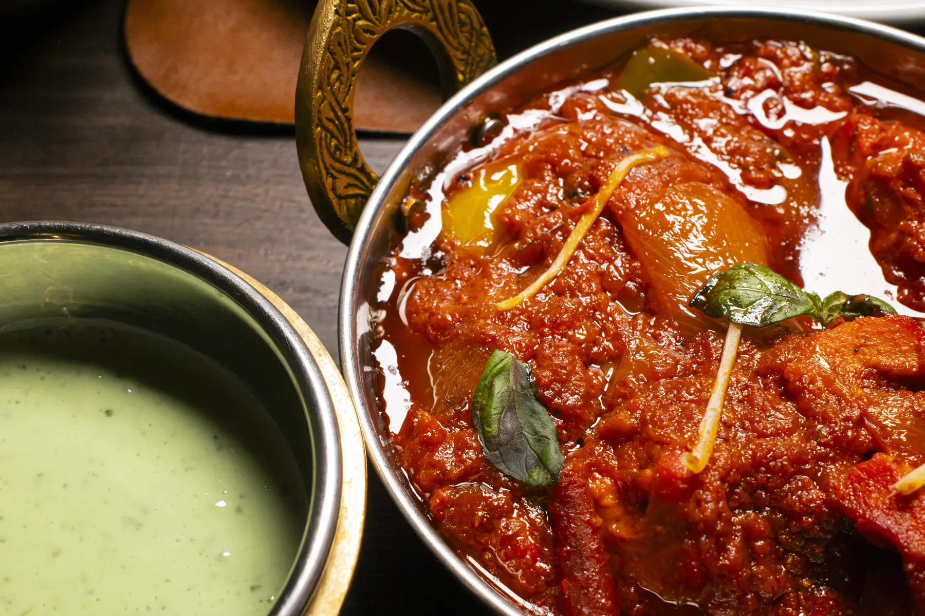 Curry rosso nella ciotola in rame, accanto al chutney alla menta