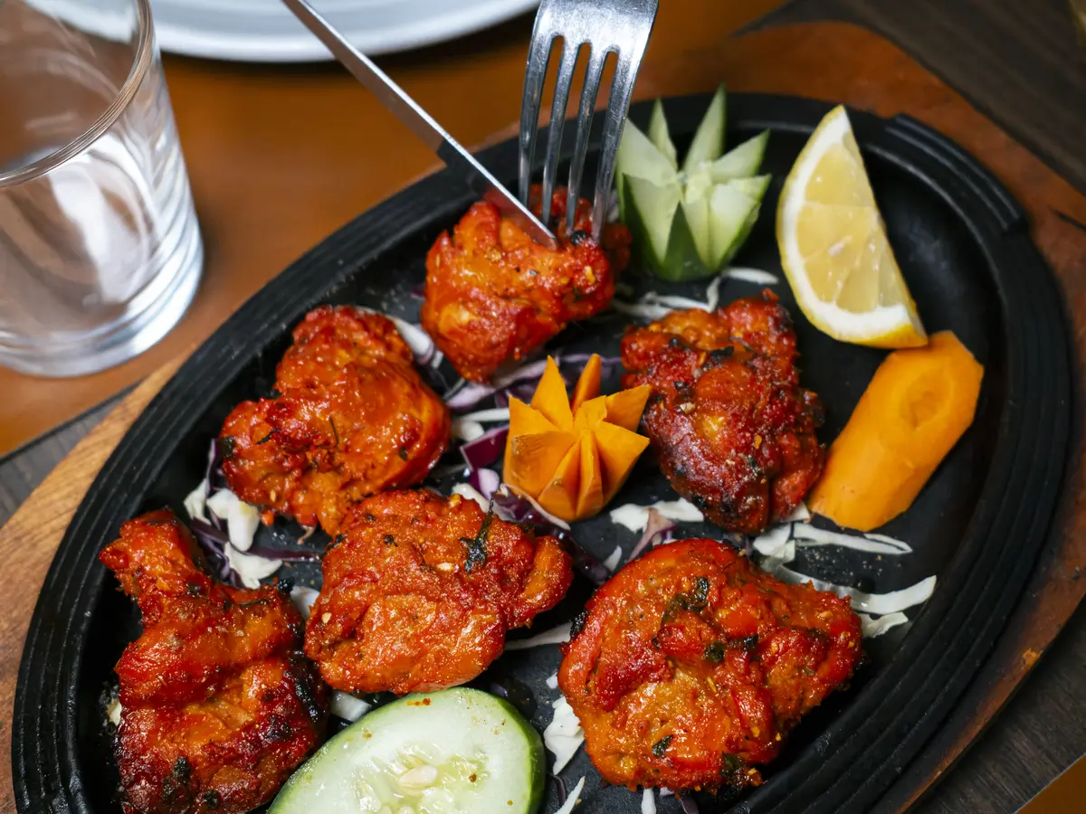 Tikka di pollo marinati alle spezie, serviti sulla piastra rovente